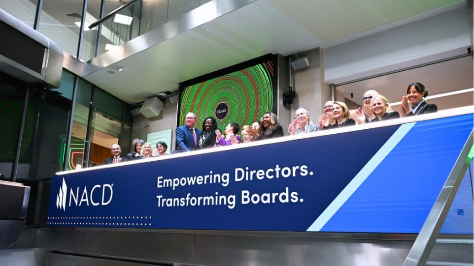 Diverse group celebrating at an NACD event behind a mission statement banner.